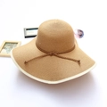 Detail of wide brim straw sun hat with white piping and ribbon on white background - Khaki
