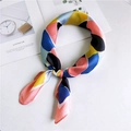 Élégant foulard en soie patchwork multicolore noué sur un fond blanc au style minimaliste - Bloc multicolore avec bord rose
