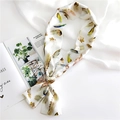 Elegant cream silk neck scarf with colorful feather print displayed on magazine - White Feather