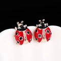 Detail of ladybug earrings with red enamel and crystals on a minimalist background - E250-1 / Red