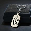 Macro shot of silver stainless steel keychain with minimalist hollow letter G pendant - Letter G / Silver