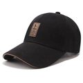Detailed shot of a black cotton baseball cap featuring a brown leather EDIKO patch and piping - Adjustable / Black
