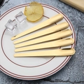 Set of five gold stainless steel flat stirring spoons on a modern white plate - 410 Stainless Steel Spoon - Gold