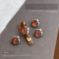 Macro-opname van 10x10mm hartvormige amberkleurige kristallen nagelbedel met parels en steentjes - 10x10mm Hartstijl (Maillard 2563)