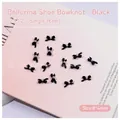 Close-up of matte black bowknot nail charms with white pearl detail for manicure - Black Bowknot (2512)