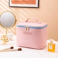 Pink portable makeup bag with double zippers and top handle in a cozy vanity setting - Rose Pink