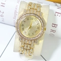 Close-up of iced-out gold watch with rhinestone dial on beige velvet pillow display - Gold