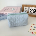 Close-up of light blue quilted heart pattern cosmetic bag with zipper and soft fabric texture - Quilted Heart Blue
