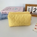 Detail of yellow quilted toiletry bag featuring heart embroidery and zipper closure - Quilted Heart Yellow