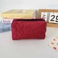 Detailed view of red heart-shaped quilted fabric and black zipper on a makeup bag - Quilted Heart Wine Red