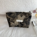 Detail of cosmetic bag showing golden butterfly patterns and May Rabbit logo tag - Gilded Butterfly Medium Cosmetic Bag