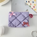 Close-up of a purple quilted cosmetic bag with pink and red checkered bows on a desk - Purple