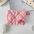 Detailed view of pink glossy quilted cosmetic pouch with cute bow accents on a desk - Deep Pink