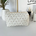 Detailed macro view of quilted floral fabric texture and zipper on makeup bag - White Base Floral