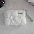 Close-up of white cloud-quilted mini pouch with brand tag and green wrist strap - Quilted Cloud Cream White
