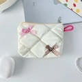 Detail of white quilted cosmetic bag with gingham bows on a lifestyle desktop - Off-white