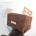 Close-up of deep brown corduroy texture and May Rabbit label on a portable storage pouch - Brown