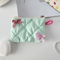 Detailed top view of a mint green quilted cosmetic bag with cute decorative bows - Light Green