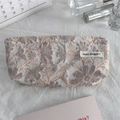 Detailed close-up of a floral jacquard makeup pouch with woven label and premium texture - Silk Galsang Flower Brown