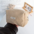 Detail der Cord-Kosmetiktasche in Khaki mit Metallreißverschluss und Webetikett - Aprikose