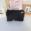 Detail of black quilted cosmetic bag featuring white bow embroidery and top zipper closure - Black Embroidered Bow