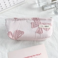 Macro shot of pink canvas cosmetic bag featuring detailed bow pattern embroidery - Pink Background Bow
