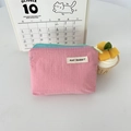 Dettaglio di una pochette in nylon a quadretti rosa con cerniera blu ed etichetta in tessuto - Rosa