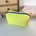 Close-up of a neon yellow quilted toiletry bag with a blue zipper and silver ring puller - Quilted Vertical Stripe Yellow