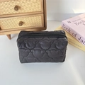 Close-up of black quilted nylon toiletry bag with cute bear stitching on a wooden desk - Quilted Cat Head Black