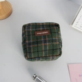 Detail of green plaid wool makeup bag with leather logo tag on a desk setup - Woolen Green Plaid (Leather Label)