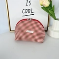 Detail van rood-crème geruite make-uptas met zilveren ritsen en een stoffen label - Rood Geruit