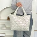 Detail of white PU tote bag featuring 3D heart quilted texture and woven brand label - Heart Creamy White