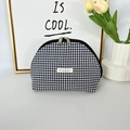 Close-up of black and white gingham shell makeup bag with brand tag and metal zipper - Black Grid