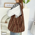 Grande borsa hobo in maglia a righe marroni e verdi in un ambiente domestico sobrio - Righe Marroni e Verdi
