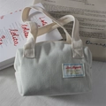 Detailed close-up of a corduroy handbag with brand patch on white magazines - Milk White Corduroy