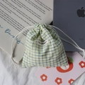 Detail of checkered drawstring storage pouch with fabric texture and woven brand label - Green Check