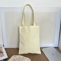 Detail shot of a minimalist blank cotton canvas tote bag on a textured carpet background - Cream Yellow (8oz)