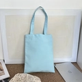 Detail view of light blue canvas tote bag next to a tablet showing its size and capacity - 8oz / Blue