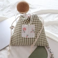 Dettaglio custodia a quadretti verdi con toppa floreale e coulisse in cotone bianco - Quadri Verdi