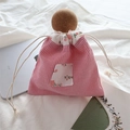 Détail de la pochette en coton à rayures rouges et poche fleurie sur literie blanche - Fines Rayures Rouges