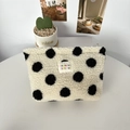 Close-up of the soft plush black and white polka dot cosmetic bag with zipper and logo label - Plush Black Polka Dot