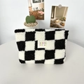 Close-up of black and white checkered plush makeup bag with soft fleece texture on white table - Plush Checkerboard Black Grid