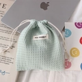 Detail of light green waffle textured drawstring pouch with May Rabbit label on desktop - Polyester Waffle Green