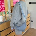 Blue nylon crescent dumpling bag with adjustable shoulder strap worn by a model - Blue