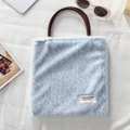 Detail of light blue leopard faux fur tote bag with dark brown round handles and brand tag - Plush Blue Leopard Print