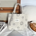 Detailed texture of white corduroy tote bag featuring minimalist black smiley face patterns - Creamy White Smiley Face