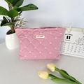 Close-up of pink quilted makeup bag with heart patterns and May Rabbit logo tag - Pink