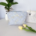 Detail of blue quilted Cinnamoroll makeup bag featuring a May Rabbit woven label - Cartoon Light Blue