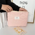 Dettaglio del beauty case rosa trapuntato con trame floreali e chiusura a zip dorata - Poliestere Floreale Rosa