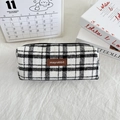 Close-up of checkered tweed pencil case with brown leather tag on minimalist desk - Woolen Large White Plaid